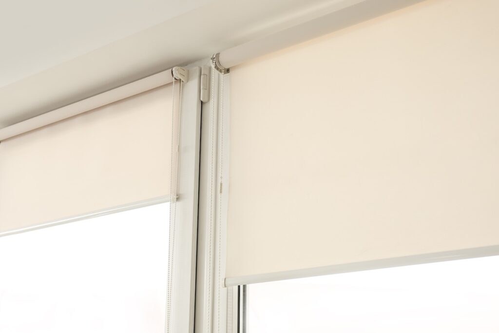 Close-up of a roller blind running in a side channel beside a window frame