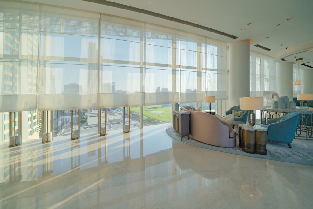 Hotel lounge with floor-to-ceiling glazing and screens along the window wall