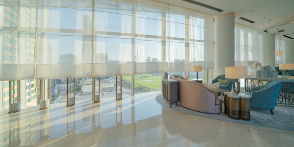 Hotel lounge with floor-to-ceiling glazing and screens along the window wall